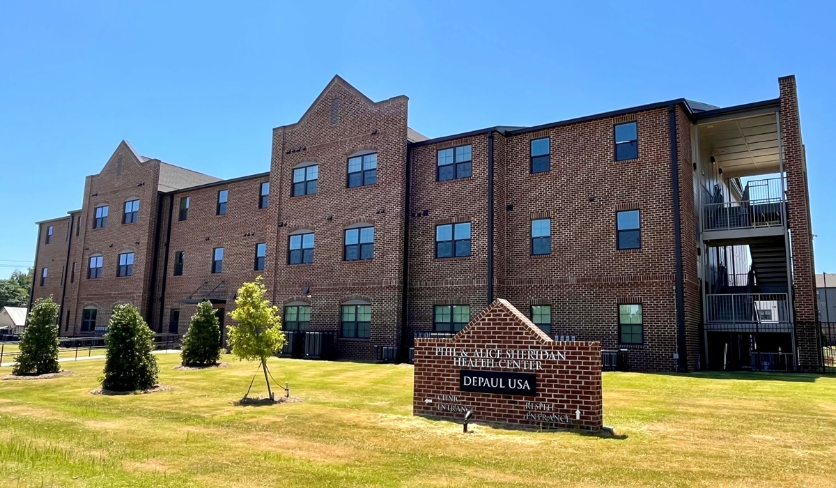 A three-story brick building with large windows houses a medical and dental health center. A sign in the foreground reads 